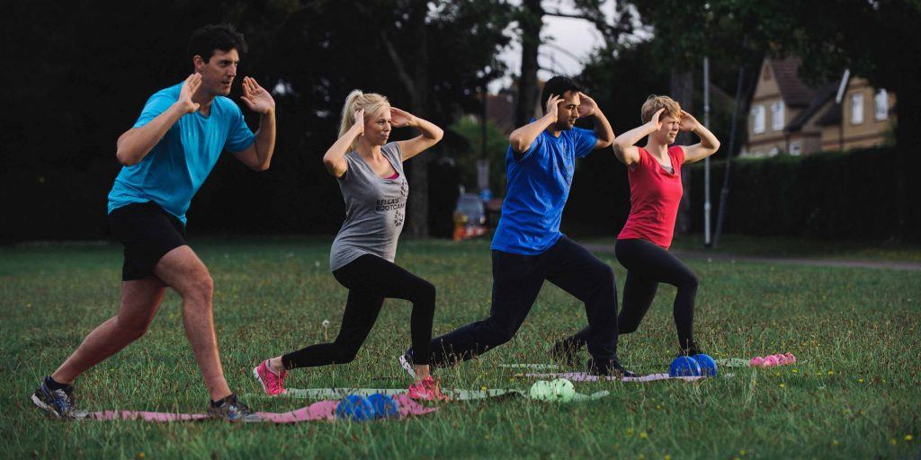a group of adults playing fitness in a park